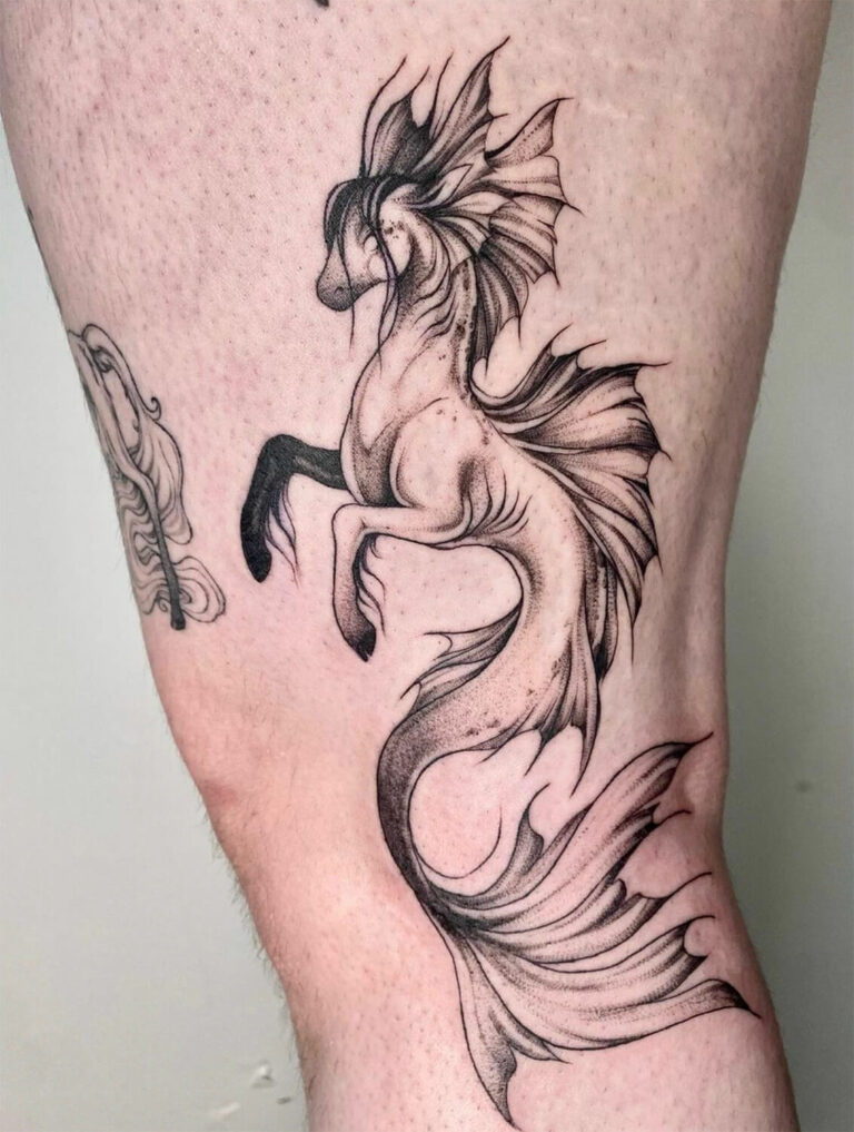 Black and grey hippocampus or kelpie tattoo on the thigh