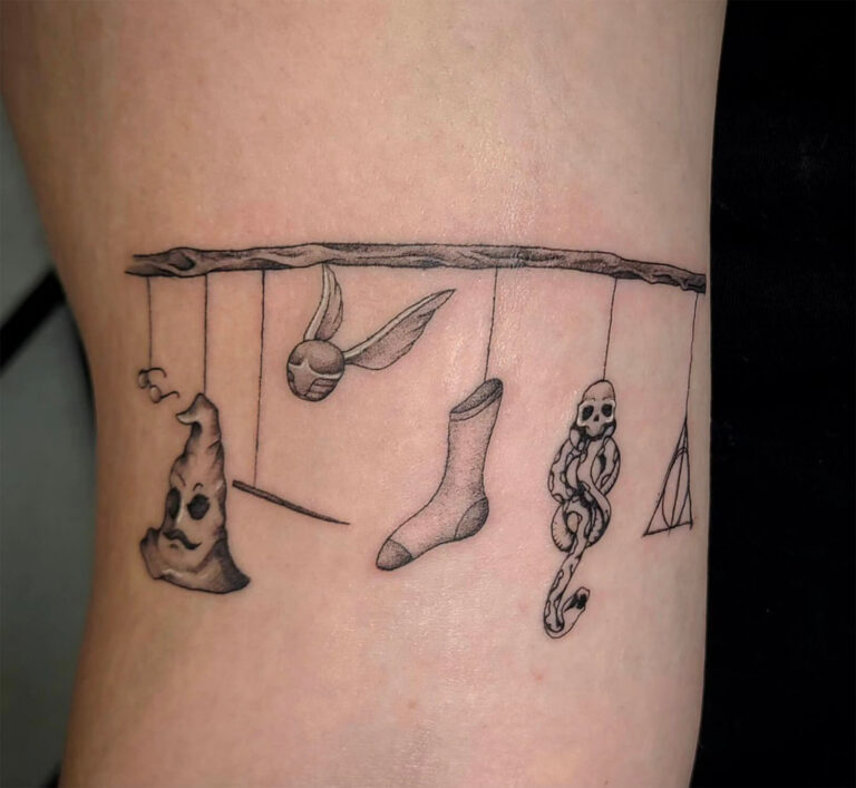 Black/grey fineline tattoo of Harry Potter items including glasses, sorting hat, wand, snitch, Dealthy Hallows symbol