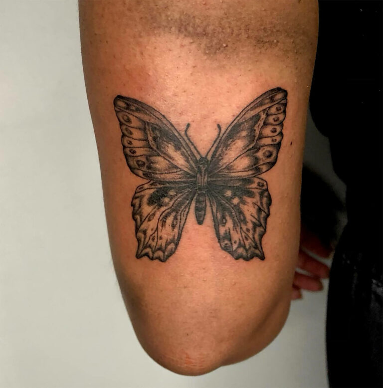 Black and grey butterfly tattoo with detailed wings on a leg by Tanya
