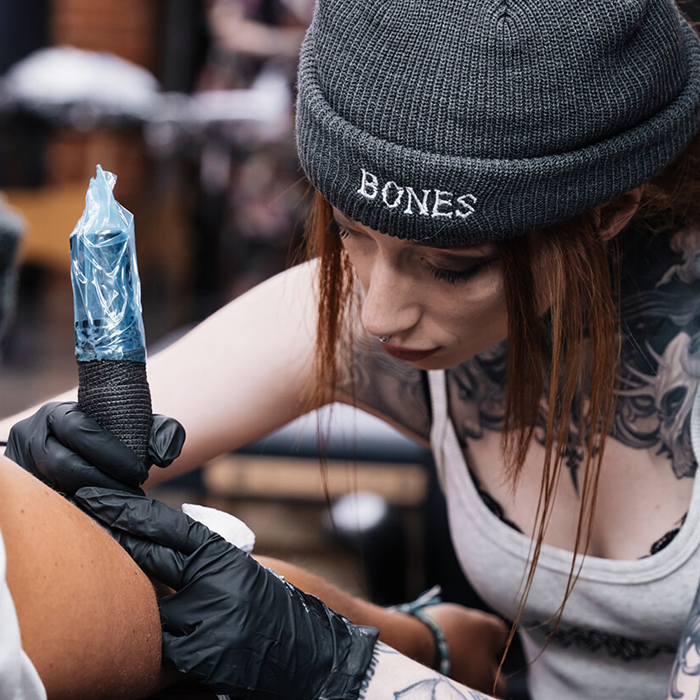 Female Melbourne tattoo artist, Syd, tattooing a client's arm