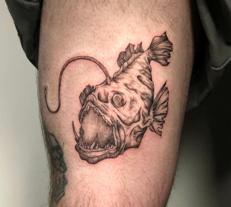 Anglerfish tattoo showing large mouth, sharp teeth, and head lure on skin.