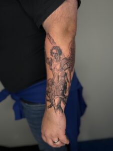 Black/grey realism tattoo of a roman warrior on forearm