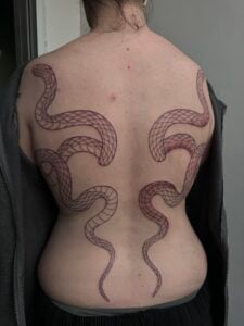 Line work on symmetrical snakes back piece tattoo