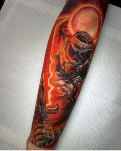 Highly saturated red and orange Doom themed tattoo on the forearm