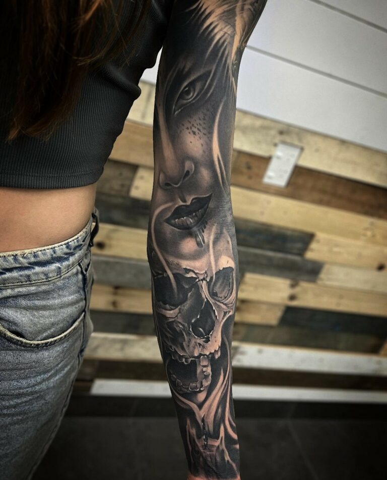 Arm tattoo of a woman's face and skull, monochrome, intricate shading, wood panel background.
