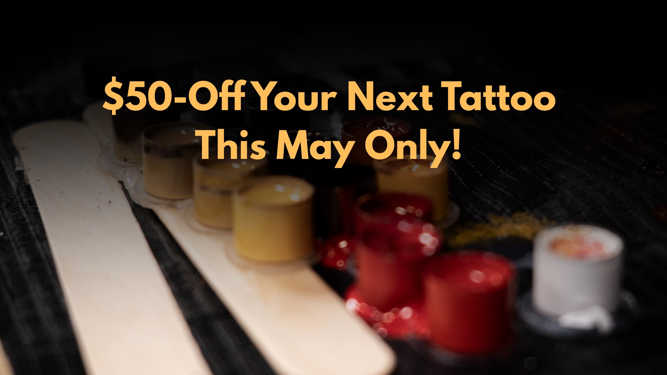 $50 tattoo discount in May, with tattoo ink pots in the background.