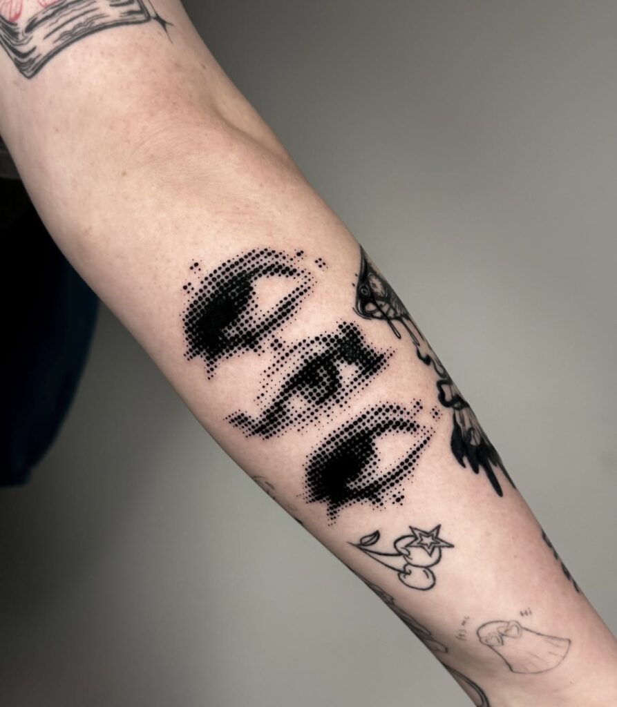 Forearm tattoo with three dotwork eyes, a cherry with star, and a ghost saying hi.