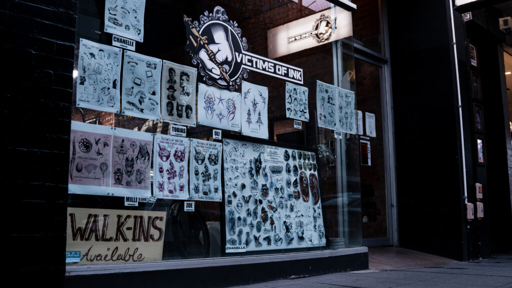 Victims of Ink Tattoo Studio window with flash tattoo designs and walk-ins available sign.