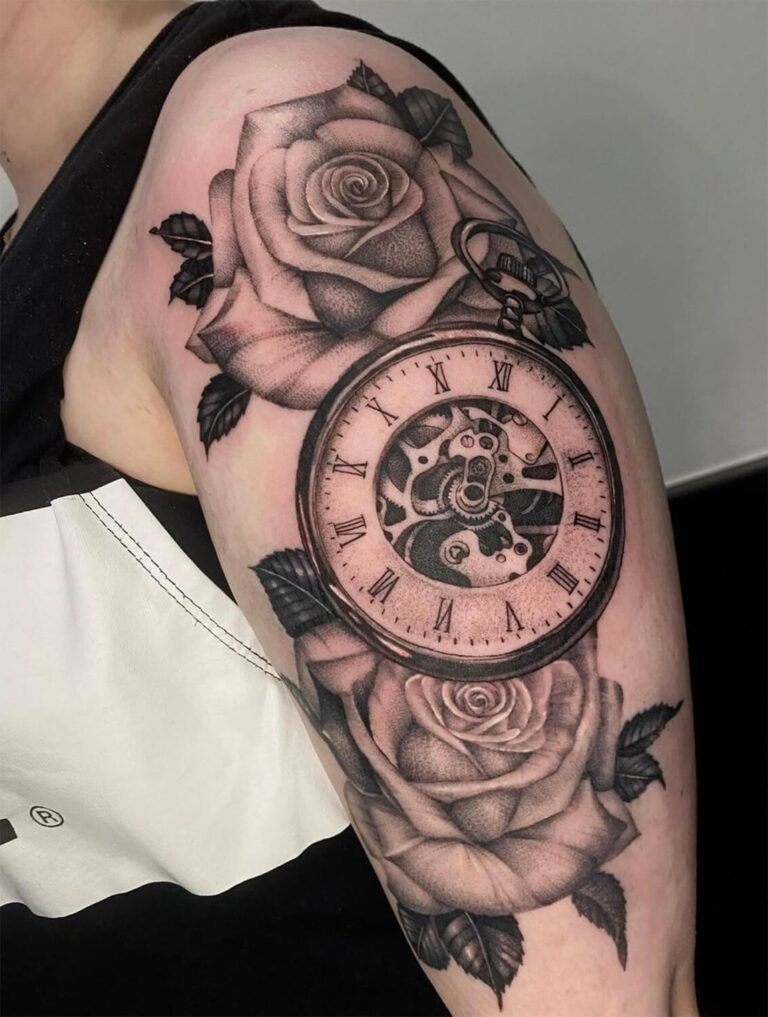 Black and grey pocket watch tattoo with two roses on the upper arm