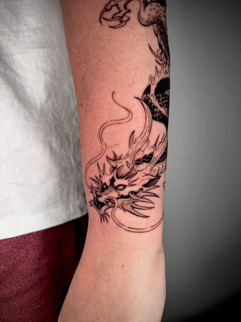 Blackwork dragon tattoo wrapping around the arm by David Carry