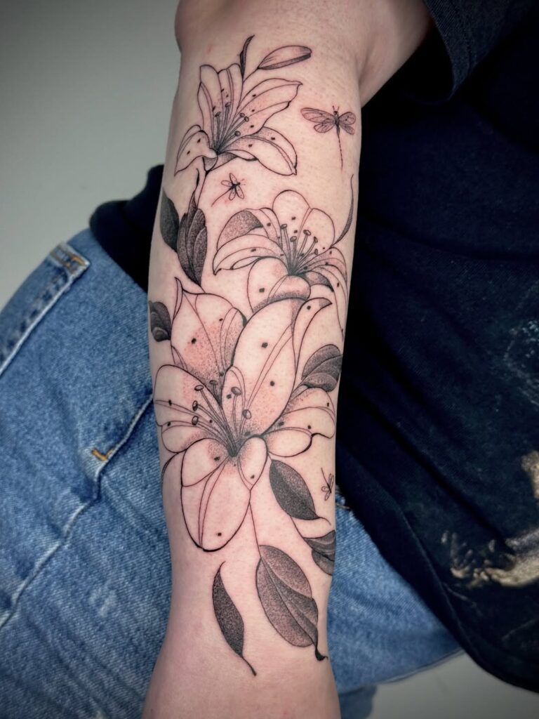 Fine-line lily and dragonfly tattoos on the forearm by David Carry