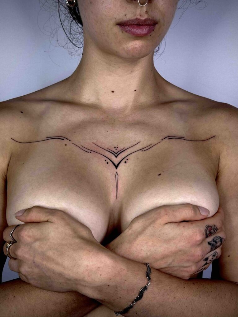 Fine-line ornamental chest tattoo by David Carry at Victims of Ink