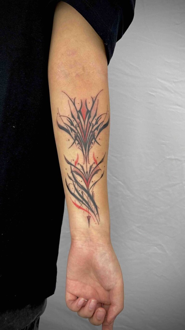 Forearm with abstract symmetrical tattoo, intricate black lines, red accents, vertical alignment.