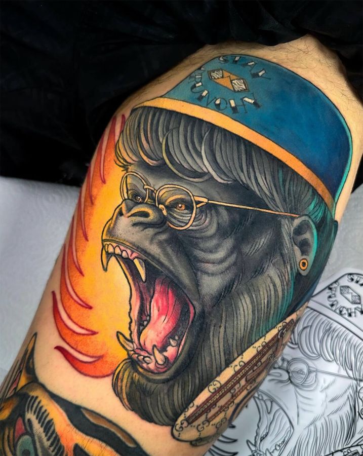 Neotraditional tattoo of a roaring gorilla wearing glasses, a bucket hat, and earrings