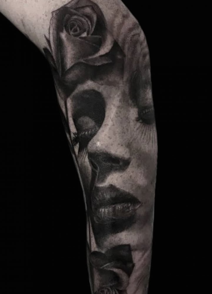 Tattoo of a woman's face with roses, blending floral and human imagery on skin.