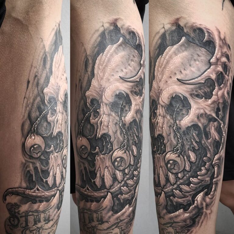 Bioorganic black/grey skull tattoo located on the thigh