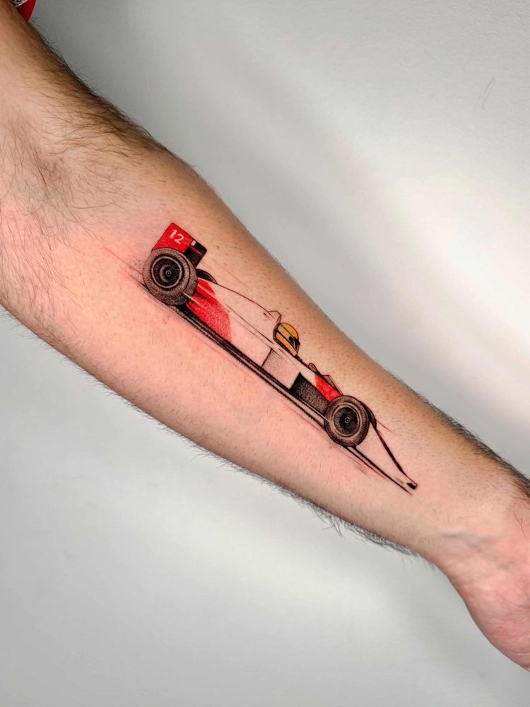 Red racing car tattoo with fine line motion trails on a forearm by Woody