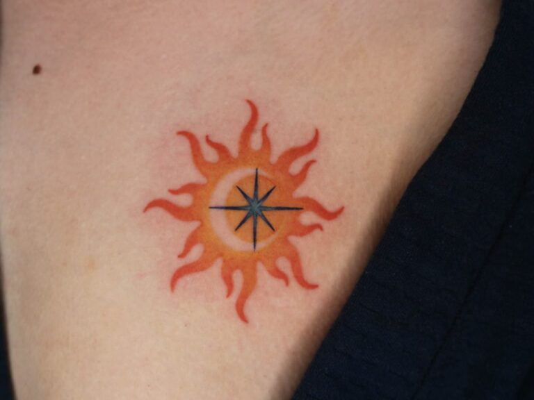 Small orange sun tattoo with a dark blue star at its centre by Woody