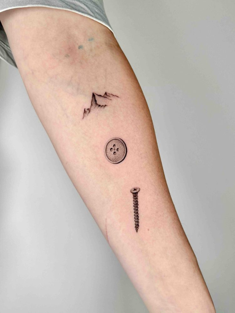 Three small tattoos of mountains, a smiling face and a sword on an arm by Woody