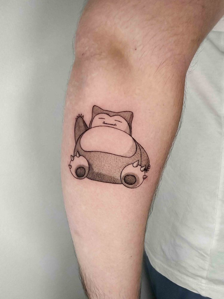 Small sleeping cartoon character tattoo with rounded shapes and soft grey shading by Woody