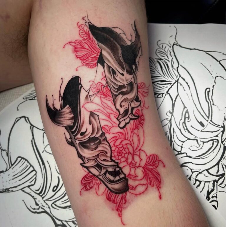 Black and grey hannya mask tattoo broken in half with red florals in the middle