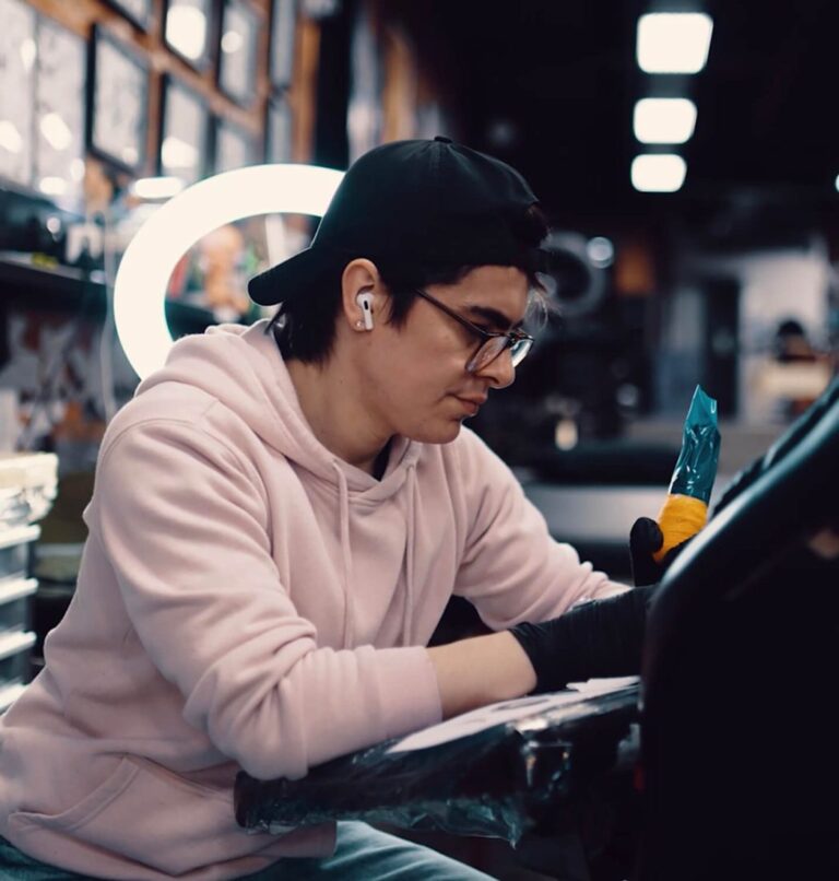Photo of male tattoo artist with backwards ball cap tattooing