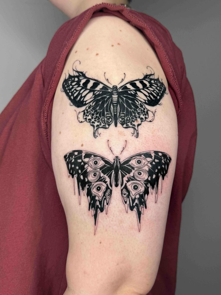 Black and white butterfly tattoos on upper arm; maroon shirt, rolled-up sleeve.