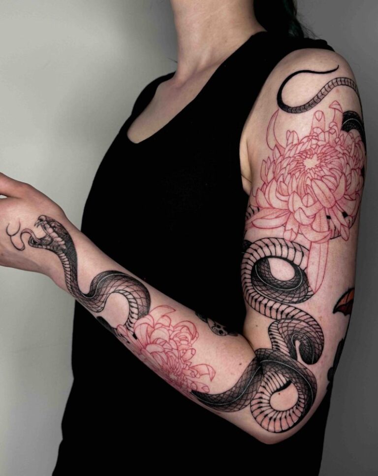 Tattooed right arm with black snake and red floral designs, sleeveless black top visible.
