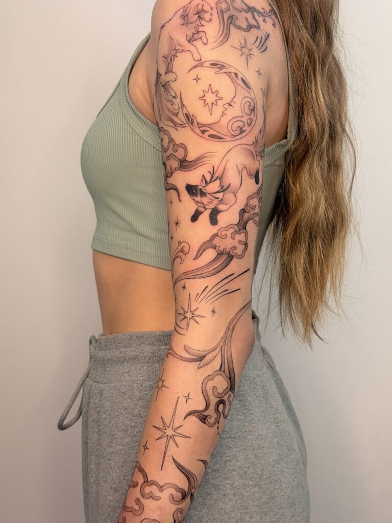 Black and grey sleeve tattoo with celestial symbols, ornamental shapes and flowing lines by Chanelle Pititto.